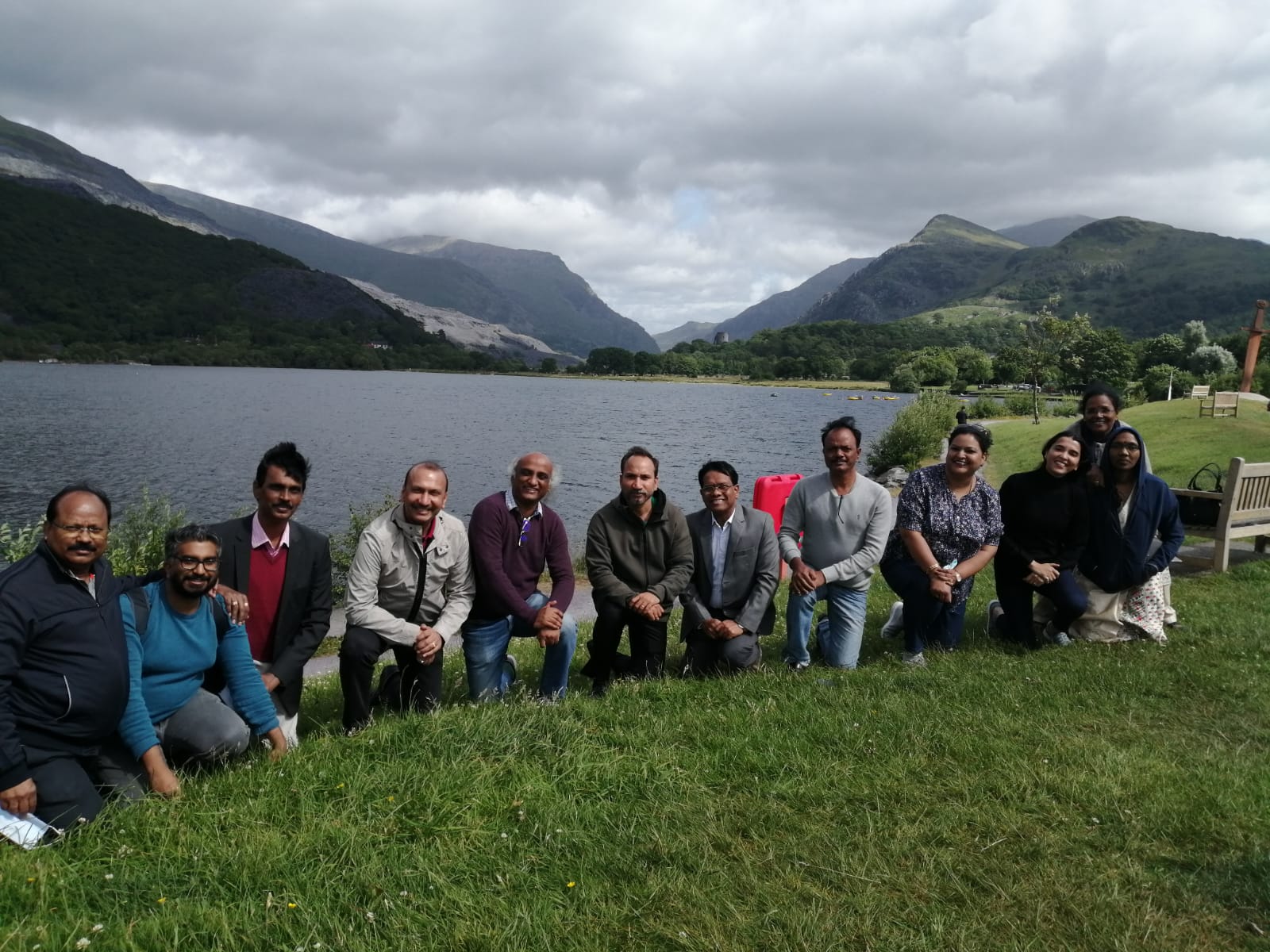 Group of people at edge of a lake with mountains in the background