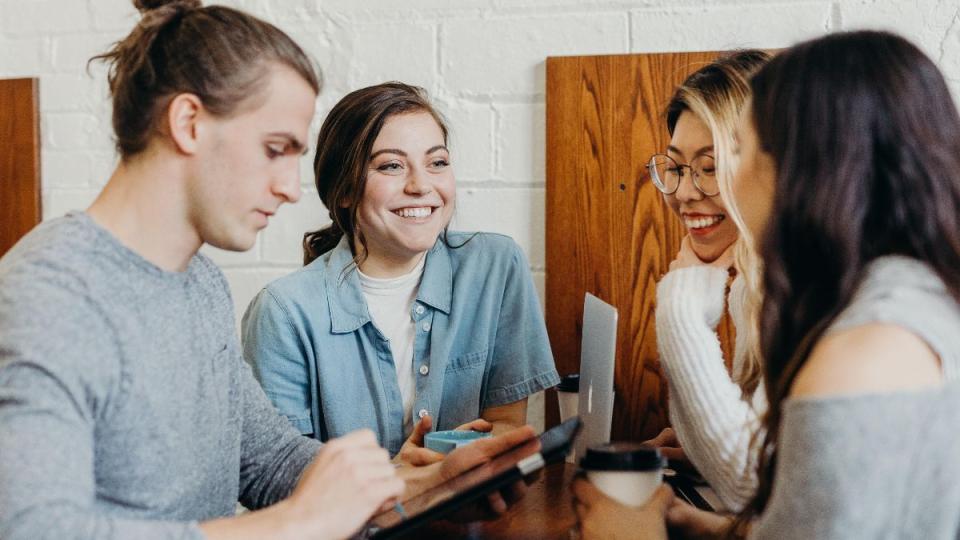 A group of students sitting at a table talking and laughing