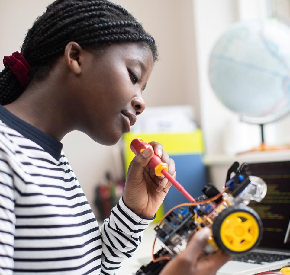 Young woman in stripy top using a screwdriver to work on an electric model car