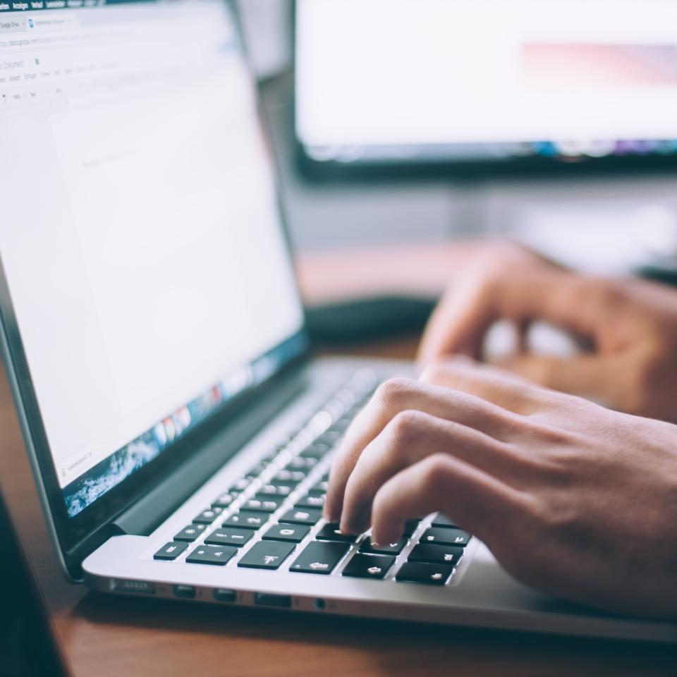 A close up of someone's hands typing on a laptop