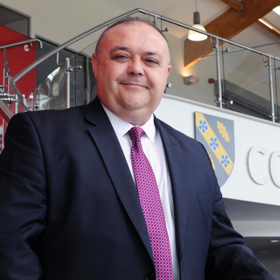 Dr Andrew Cornish standing in front of a Coleg Sir Gar sign