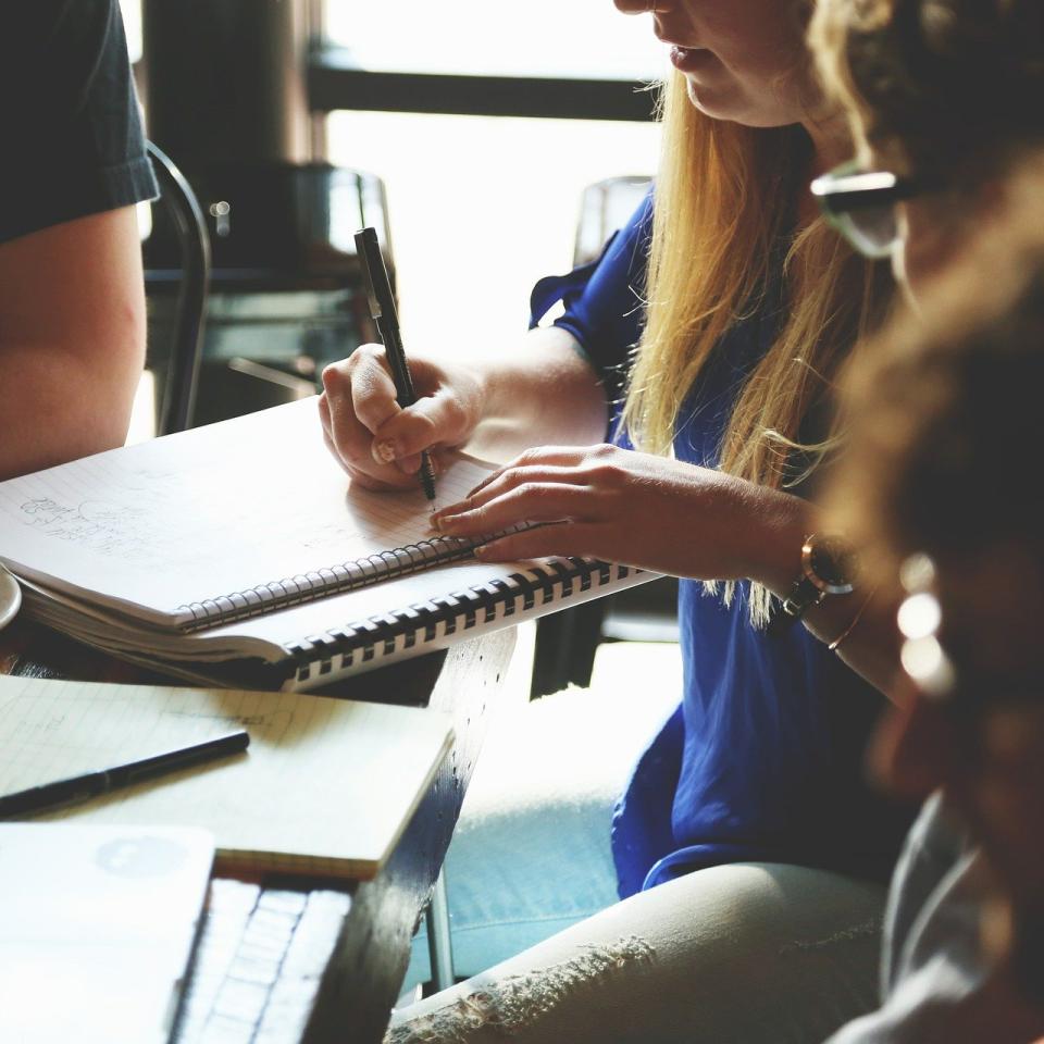 Group of people sat around a table with laptop and notepad