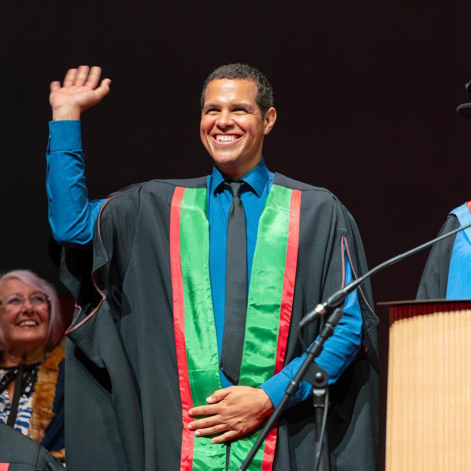 Photo of Ben Thompson on stage at graduation