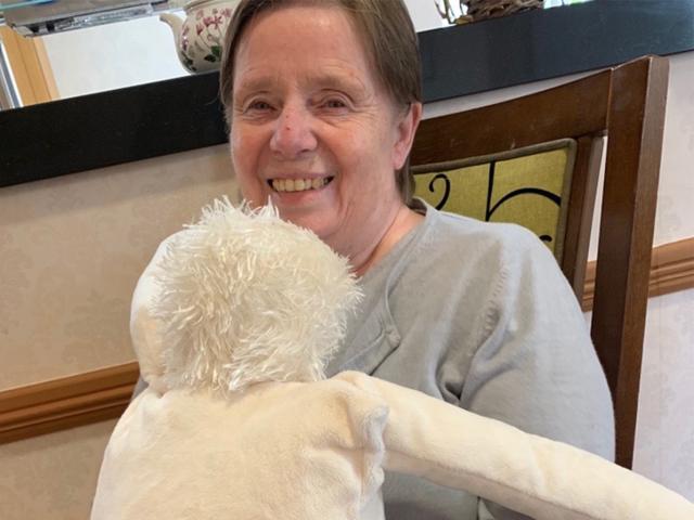 Lady sitting in chair hugging a cuddly toy