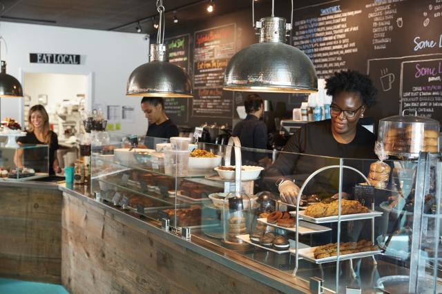 Four women serving behind the counter of a coffee shop