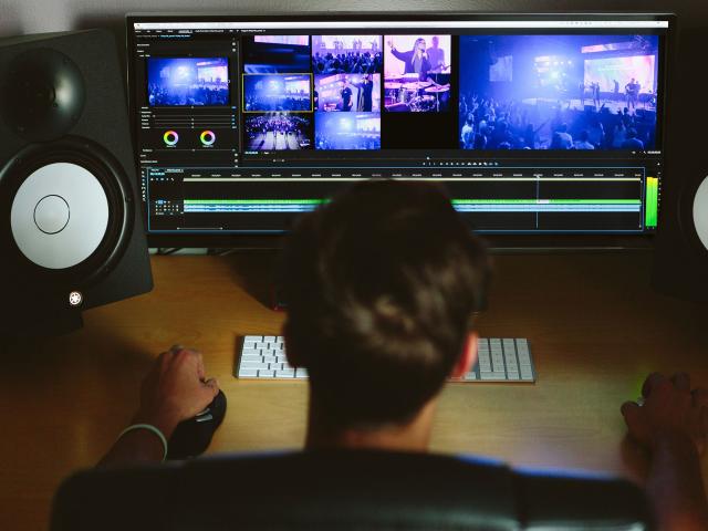 The back of person's head as they work on a computer showing visuals of a stage show