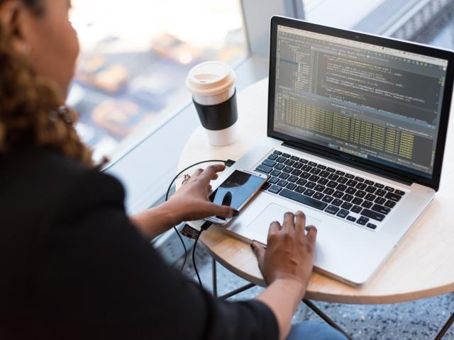 A woman sat at a small round table working on a laptop
