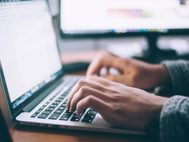 A close up of someone's hands typing on a laptop