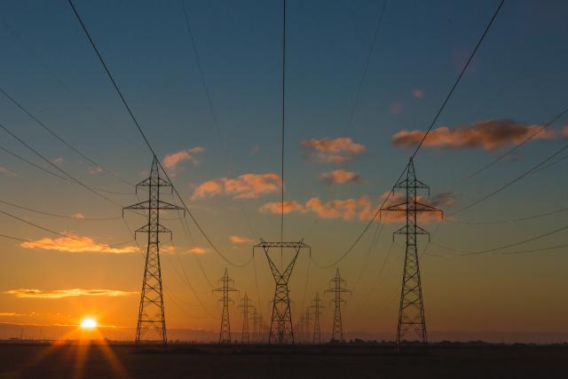 electricity pylons against a sunset