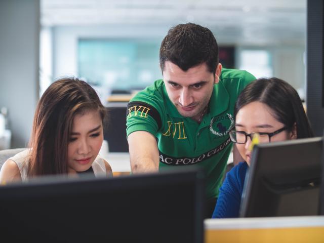 Two female students and a male teacher working on computers
