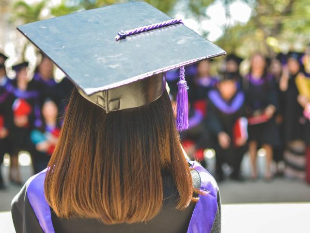 Female graduate looking out at a crowd of graduating students