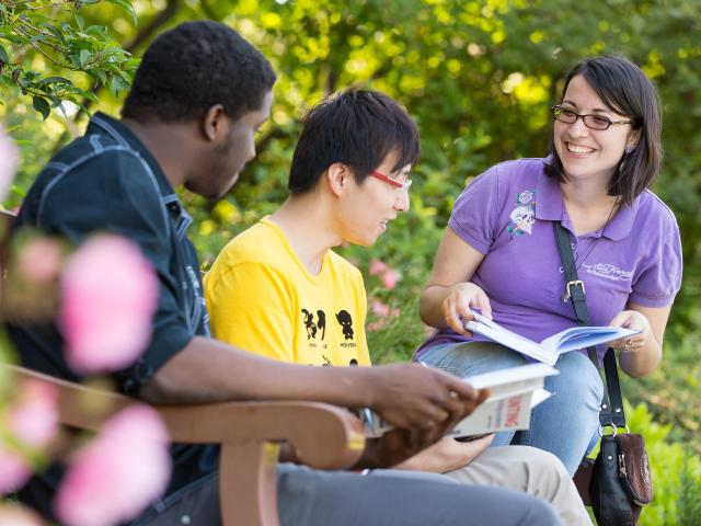 Three students sat on a bench, talking to each other