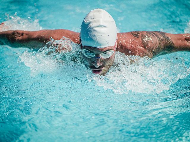 Close up shot of a man swimming butterfly in a pool