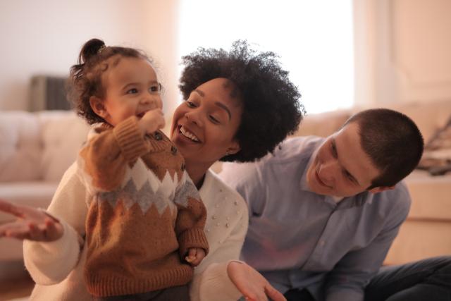 A mother and father playing with their young child
