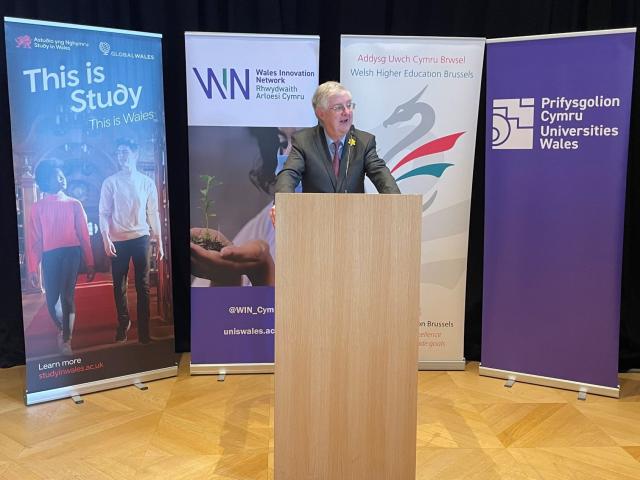 Mark Drakeford speaking in front of pop-ups