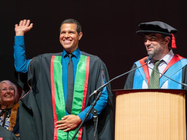 Photo of Ben Thompson on stage at graduation
