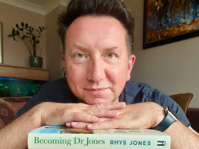 Rhys Jones with a pile of books that he authored