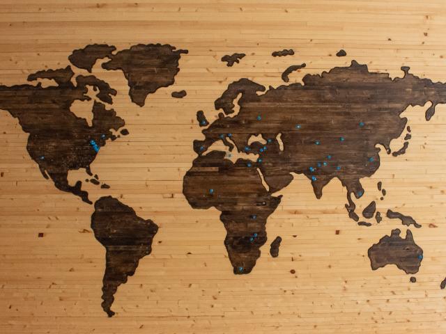 Wooden map of the world with blue pins in various locations